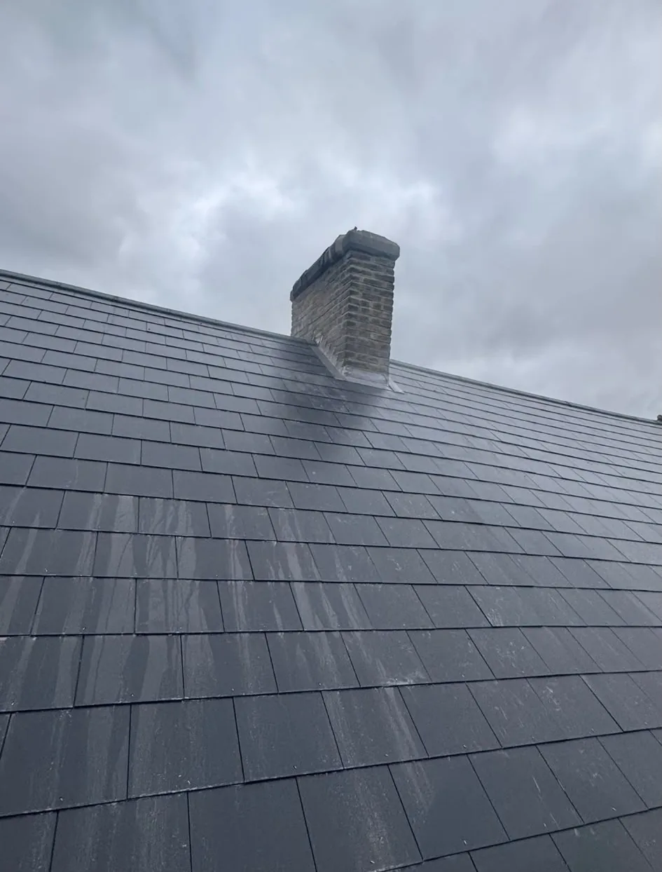 New slate roof finished around a brick chimney with fresh lead flashing