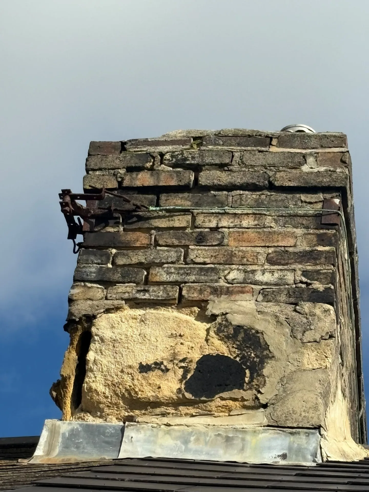Chimney stack before repair with crumbling stone, failed render and open mortar joints