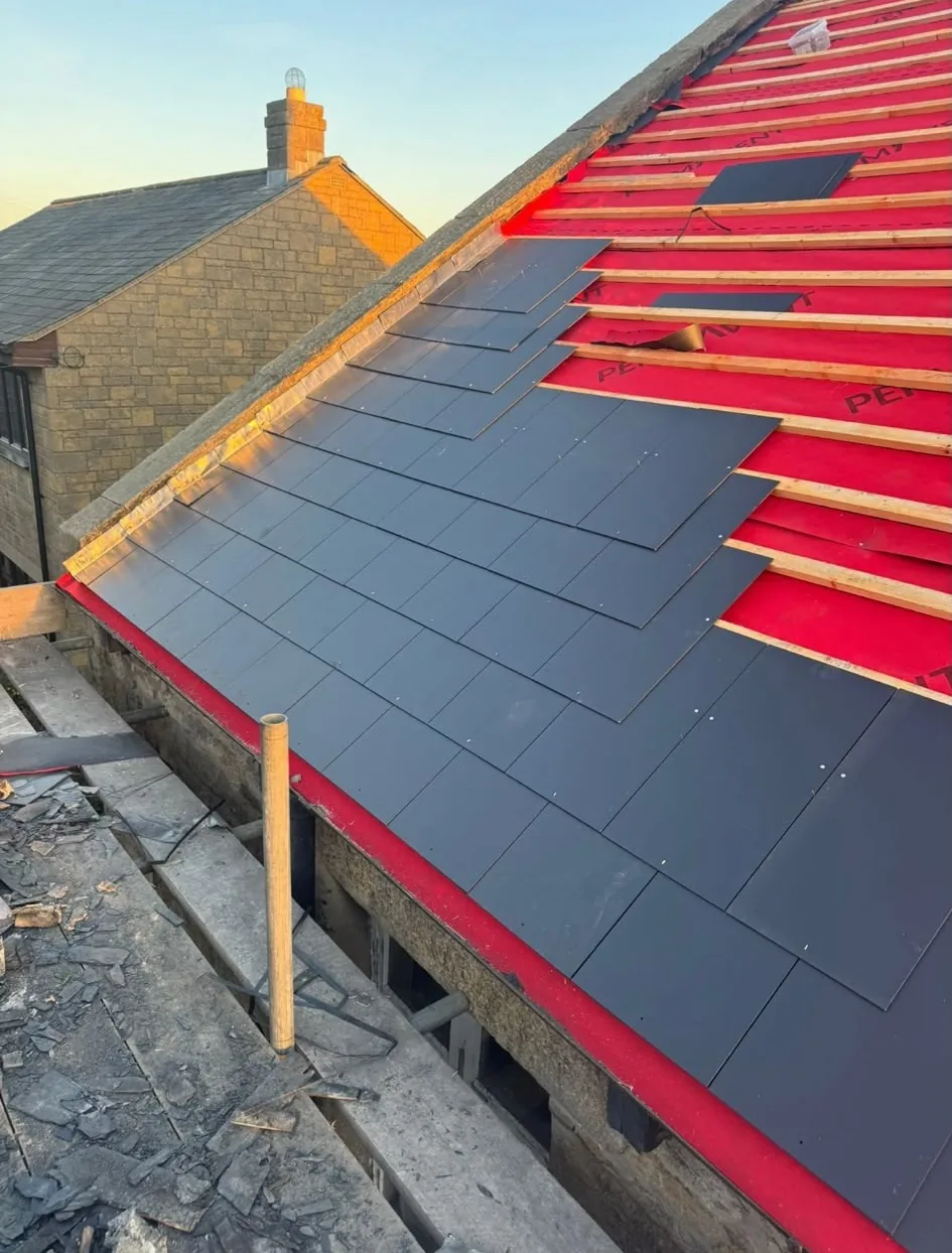 New roof installation in progress with slates fixed over membrane and battens at sunset