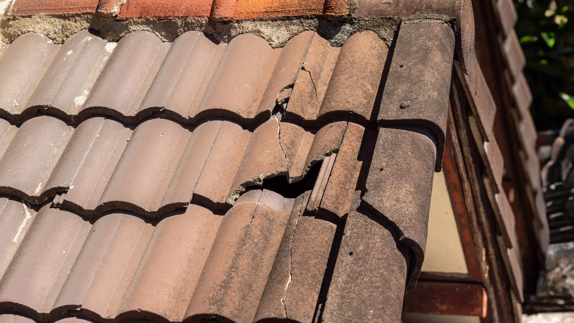 Cracked and broken roof tiles leaving a hole at the roof edge, needing an emergency repair